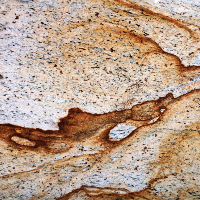 Puede incluir: Primer plano de una encimera de granito de color marr&oacute;n claro y blanco con vetas y motas marrones.