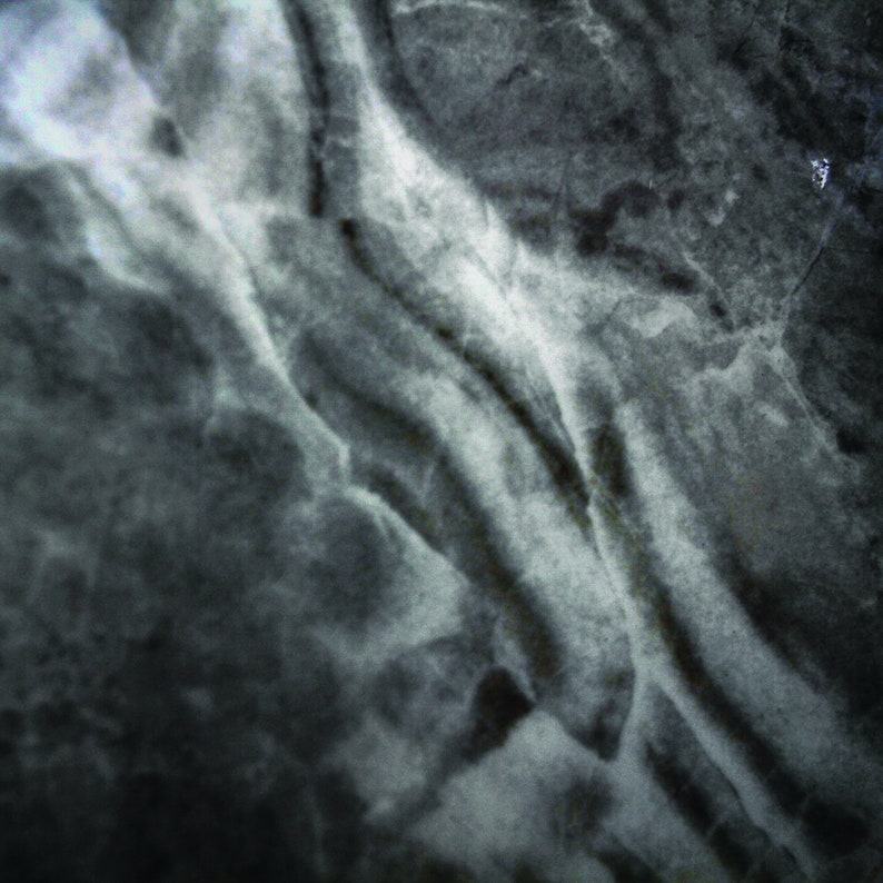May include: A close-up of a dark grey marble surface with white veins. The surface has a smooth, polished texture.