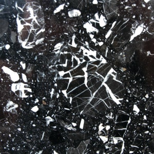 May include: Black marble with white veins and small white flecks. The marble has a polished finish.
