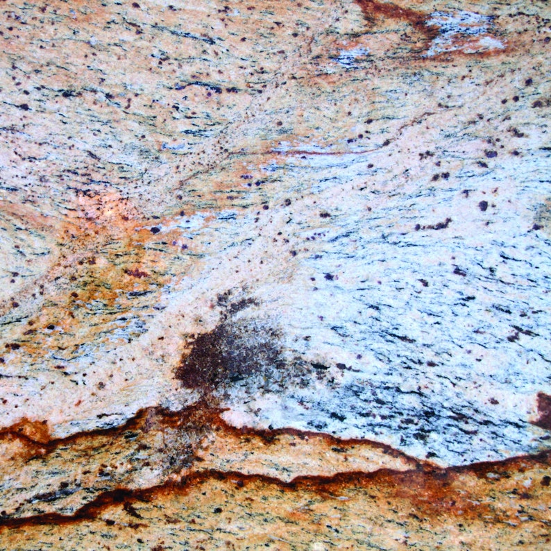 Puede incluir: Primer plano de una encimera de granito colorida con un patr&oacute;n de remolino de marr&oacute;n, amarillo, azul y blanco. La superficie tiene una textura rugosa.