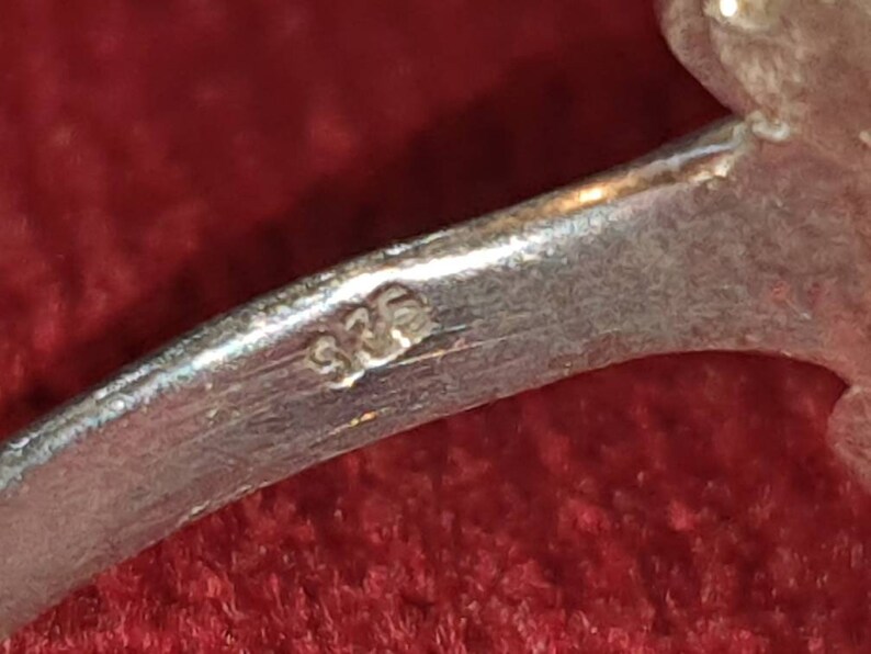 May include: Close-up of a silver ring with the number "925" stamped on the inside band.