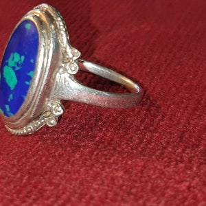 May include: A silver ring with an oval-shaped blue and green gemstone set in a decorative silver bezel.