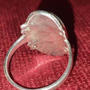 May include: Silver ring with a detailed design on the band and a large oval-shaped stone setting.