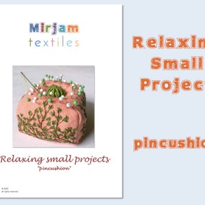 Może przedstawiać: Różowe podkładka na szpilki z zielonym haftem i białymi i zielonymi szpilkami. Podkładka na szpilki to mały, relaksujący projekt. Tekst "Relaxing small projects 'pincushion'" znajduje się na dole obrazu.