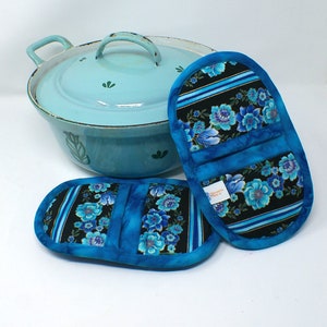 May include: Two blue and black floral pot holders with a light blue enamel Dutch oven in the background.