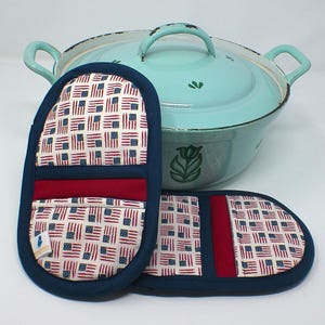 Könnte beinhalten: Ein Set aus zwei Ofenhandschuhen und einem türkisfarbenen Emaille-Topf. Die Handschuhe zeigen ein sich wiederholendes Muster aus amerikanischen Flaggen in Rot, Weiß und Blau. Die Handschuhe sind mit marineblauem Stoff eingefasst. Der Topf hat ein Fassungsvermögen von ca. 5 Litern.