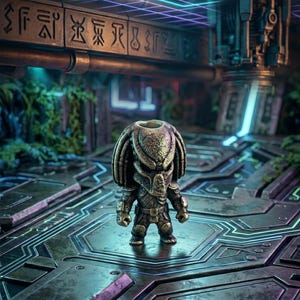 May include: A small, metallic-toned figurine of a creature with a distinct helmet, dreadlocks, and textured armor. The figure stands on a dark, geometric platform with engraved markings and blue light accents, featuring the text VOLDERWORKS.