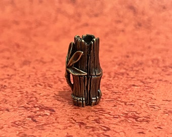 May include: A bronze-colored metal bead shaped like a bamboo stalk with a leaf detail. The bead is designed to be used as a fidget toy or a decorative element.