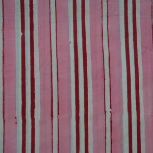 May include: A textile featuring a vertical stripe design. The stripes are in alternating colours of white, dark red, and light pink. The fabric has a slightly textured look, with the colours appearing to bleed slightly.