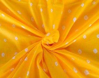 May include: Yellow fabric with a white tie-dye pattern. The fabric is folded and twisted, creating a swirling effect.