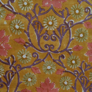 Peut inclure: Un motif de tissu sur fond jaune moutarde avec des éléments floraux répétitifs. Le design comprend des fleurs vert clair ressemblant à des marguerites, des feuilles d'érable roses et des structures en forme de vigne violet foncé.