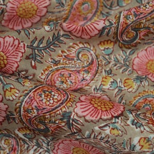 Peut inclure: Un tissu beige avec un imprimé floral composé de fleurs roses et jaunes et de motifs paisley.