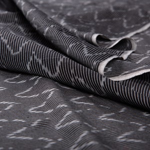 May include: Black and white striped fabric with a subtle pattern. The fabric is folded and draped, showing the texture and weave.