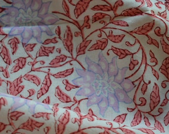 May include: White fabric with a pink and purple floral pattern. The fabric has a repeating pattern of leaves and flowers.