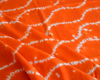 May include: Orange fabric with a white tie-dye pattern. The fabric is folded and has a soft, textured appearance.