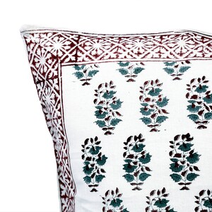 May include: White cotton pillow cover with a red and white border and a green and brown floral pattern.