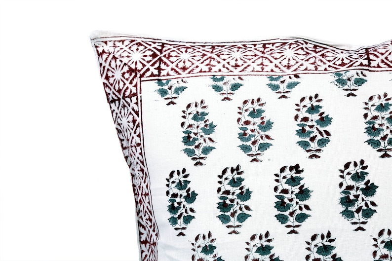May include: White cotton pillow cover with a red and white border and a green and brown floral pattern.