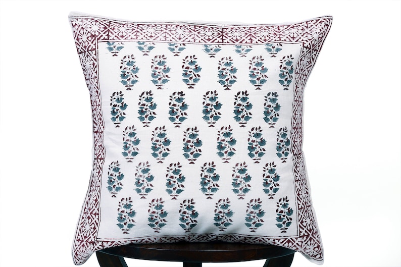 May include: White cotton pillow cover with a burgundy border and a repeating pattern of teal blue floral motifs.