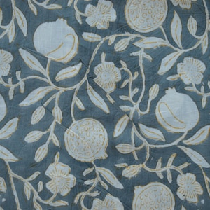 May include: A close-up of a fabric with a repeating pattern of white pomegranates, flowers, and leaves on a muted teal background. The design has a hand-drawn aesthetic, with visible texture and slight variations in the print.