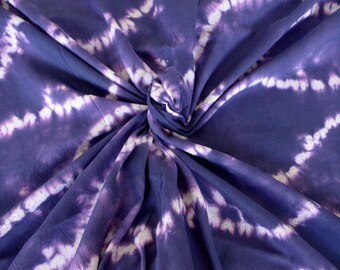 Puede incluir: Tela de tie-dye púrpura con un patrón de remolino blanco. La tela es suave y lisa, y sería perfecta para hacer ropa, accesorios o decoración del hogar.