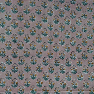 May include: A fabric with a repeating floral pattern. The flowers are yellow and gray with teal green leaves, set against a pale pink background. The design is evenly spaced across the fabric.