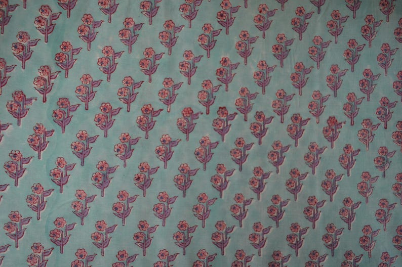 May include: A repeating pattern of stylized floral sprigs on a teal background. Each sprig features pink flowers and purple stems and leaves. The design is evenly spaced across the fabric.