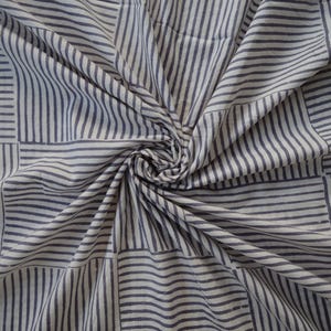 May include: White fabric with a blue and white striped pattern. The fabric is folded and twisted, creating a swirling effect.