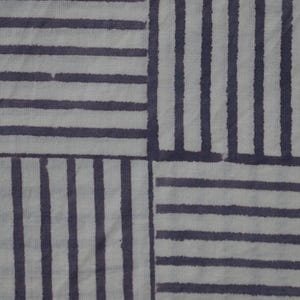 May include: A white fabric with a geometric pattern of dark gray stripes. The stripes are arranged in a grid pattern, creating a series of squares.