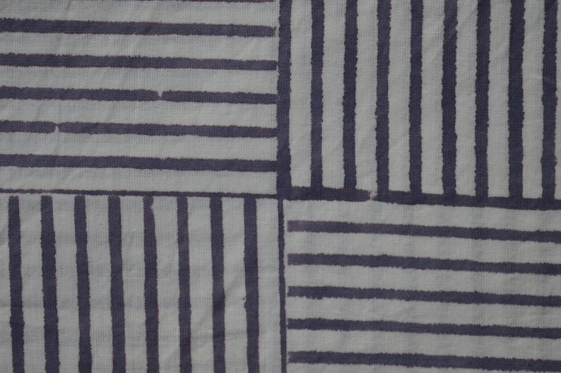 May include: A white fabric with a geometric pattern of dark gray stripes. The stripes are arranged in a grid pattern, creating a series of squares.