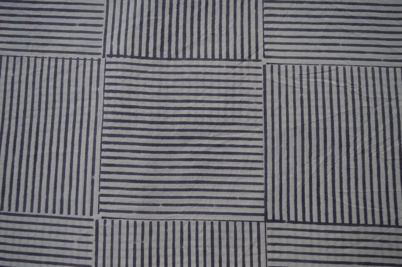 May include: A white fabric with a pattern of black stripes forming a grid.