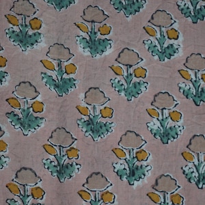 May include: A fabric with a repeating floral pattern. The design features stylized flowers in shades of beige, yellow, and green, set against a soft pink background. The flowers have a simple, block-print style, creating a vintage aesthetic.