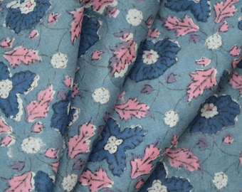 May include: A blue fabric with a floral pattern. The fabric features pink and white flowers with blue leaves on a light blue background.