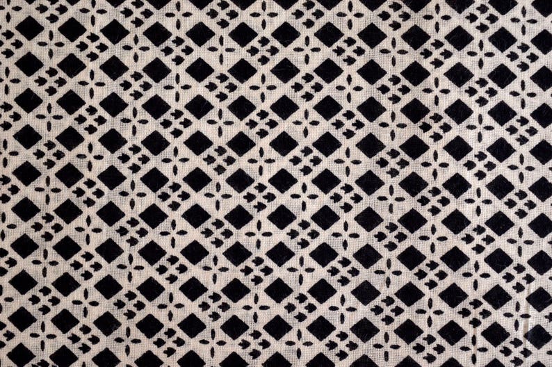 May include: Black and white geometric pattern on a white fabric background. The pattern is made up of small diamonds and squares.