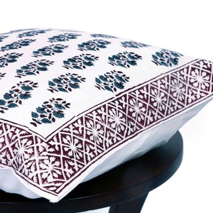 May include: White cotton pillow cover with a dark blue floral pattern and a maroon border with a geometric design.