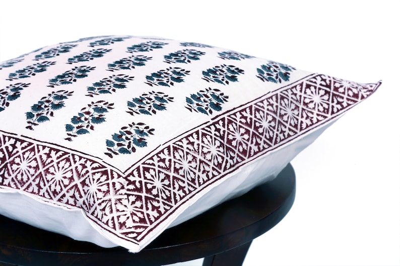 May include: White cotton pillow cover with a dark blue floral pattern and a maroon border with a geometric design.