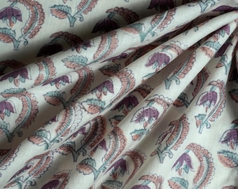 May include: White fabric with a repeating pattern of pink and green floral designs. The fabric has a soft, flowing texture.