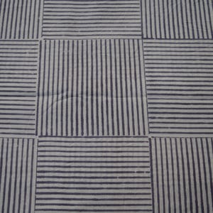 May include: A white fabric with a black striped pattern. The fabric is woven in a grid pattern with alternating horizontal and vertical stripes.