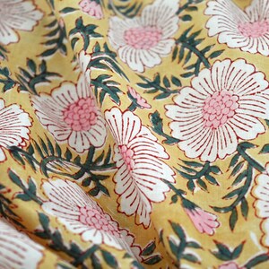 May include: Yellow fabric with a white and pink floral print. The fabric has a textured, hand-printed look.