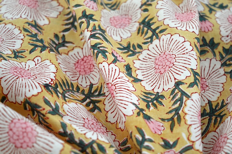 May include: Yellow fabric with a white and pink floral print. The fabric has a textured, hand-printed look.