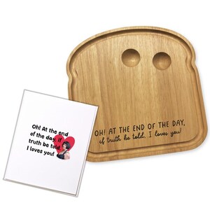 May include: A wooden bread-shaped serving board with two circular indentations. The board has the engraved text "OH! AT THE END OF THE DAY, if truth be told. I loves you!" A white card with text and a heart graphic is next to the board.