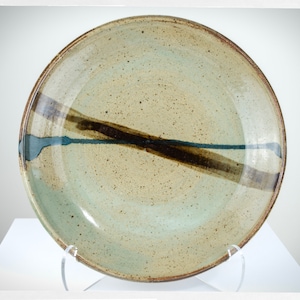 Peut inclure: Une grande assiette ronde en céramique avec un glaçage brun clair et un motif de rayures brun foncé et bleu.