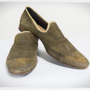 Puede incluir: Un par de mocasines de ante verde con suela marr&oacute;n claro. Los mocasines tienen un aspecto ligeramente desgastado.