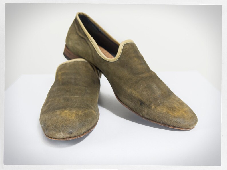 Puede incluir: Un par de mocasines de ante verde con suela marr&oacute;n claro. Los mocasines tienen un aspecto ligeramente desgastado.
