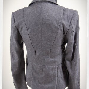 May include: A gray blazer with a fitted silhouette and a single-breasted closure. The blazer has a smooth, textured fabric and a classic design.