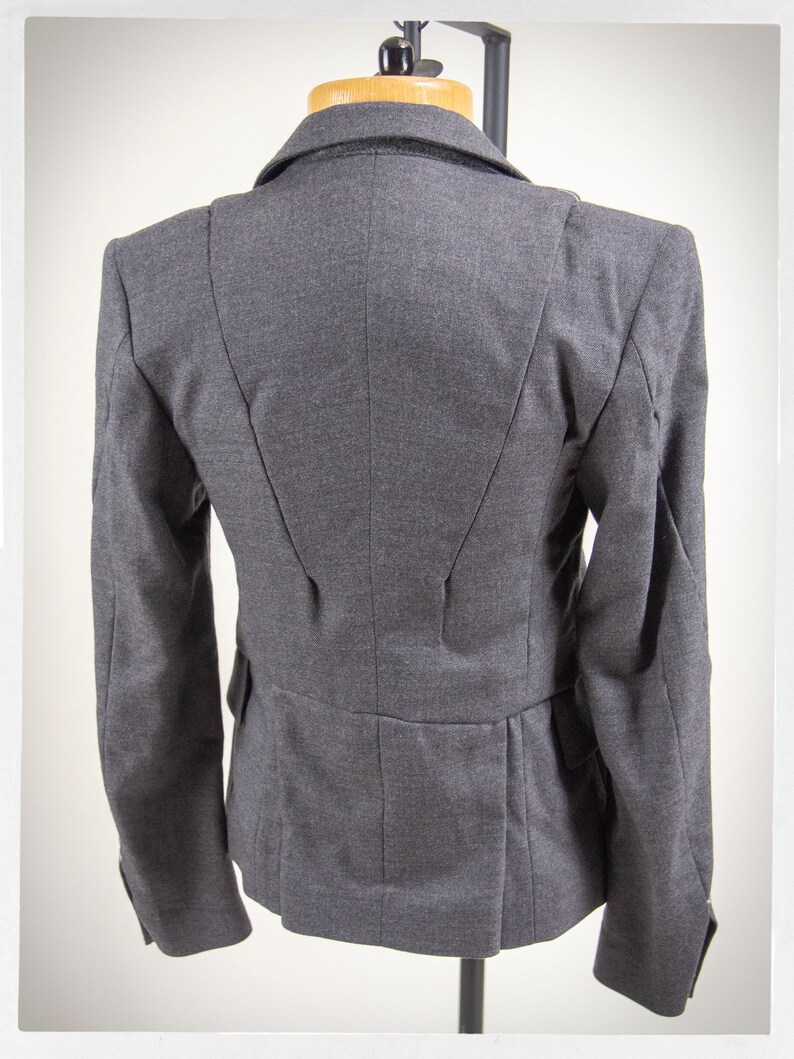 May include: A gray blazer with a fitted silhouette and a single-breasted closure. The blazer has a smooth, textured fabric and a classic design.