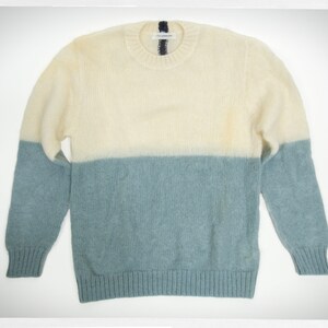 May include: A cream and light blue knitted sweater with a crew neck.