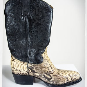 Peut inclure: Une paire de bottes de cowboy avec une tige en cuir noir et un motif en peau de serpent sur la partie inférieure de la botte.