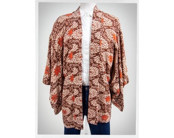 May include: A brown and white patterned kimono with orange floral designs. The kimono is on a white mannequin and has long sleeves.