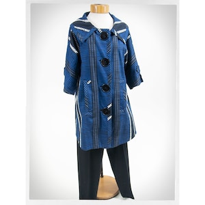 May include: A blue and white patterned jacket with black buttons and a collar. The jacket is on a mannequin and has a long, fitted style.