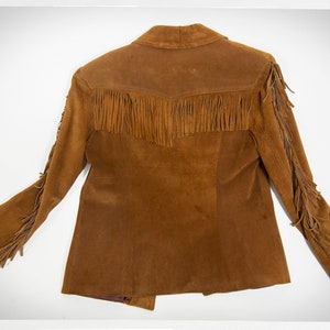 May include: A brown suede jacket with fringe detailing on the sleeves and bottom hem.